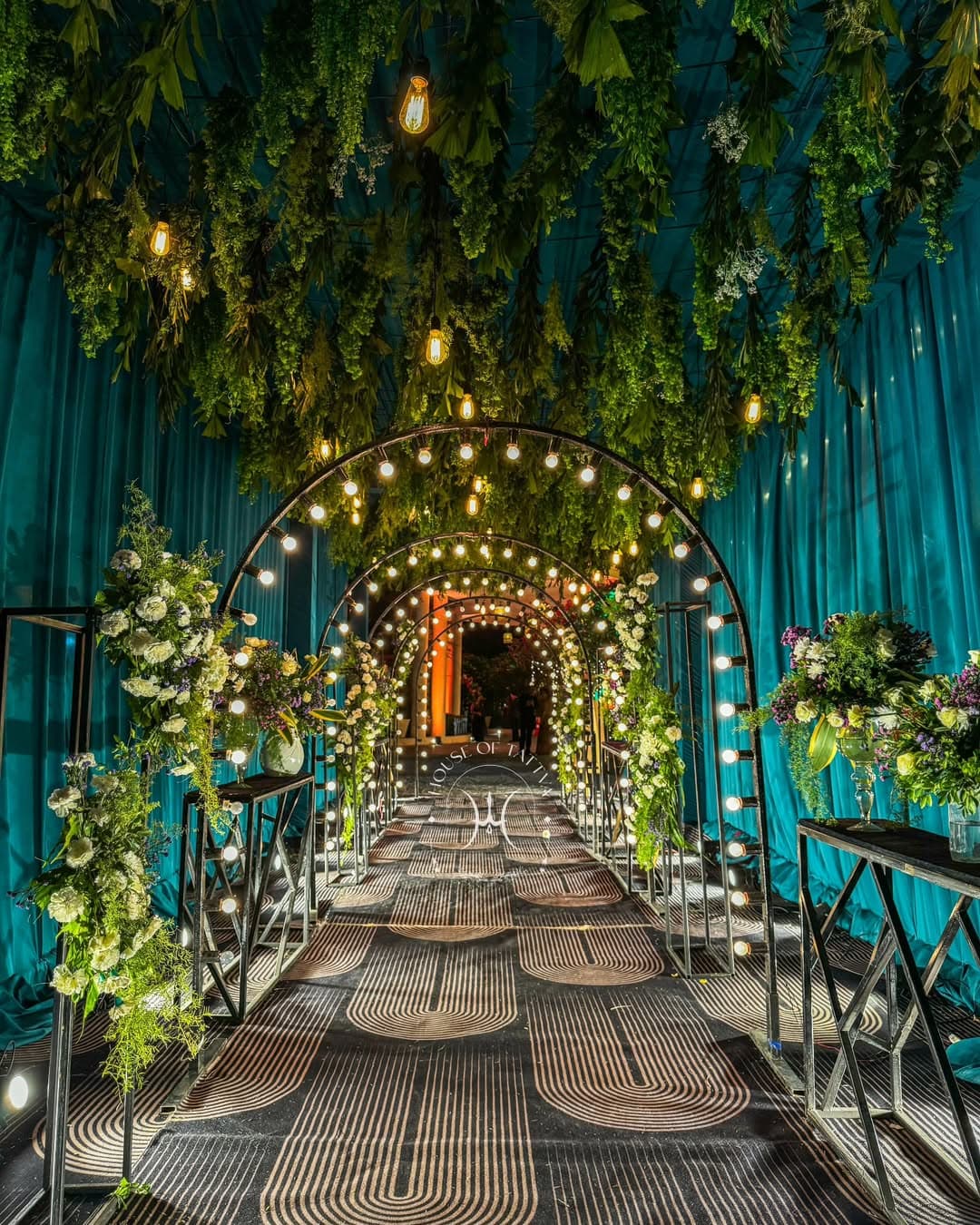 A captivating floral archway adorned with white flowers and greenery, set over tranquil water, creating a romantic ambiance.